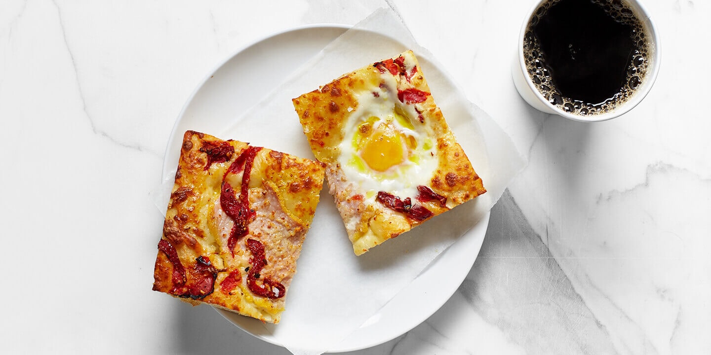 Focaccia with an egg on top and a black coffee