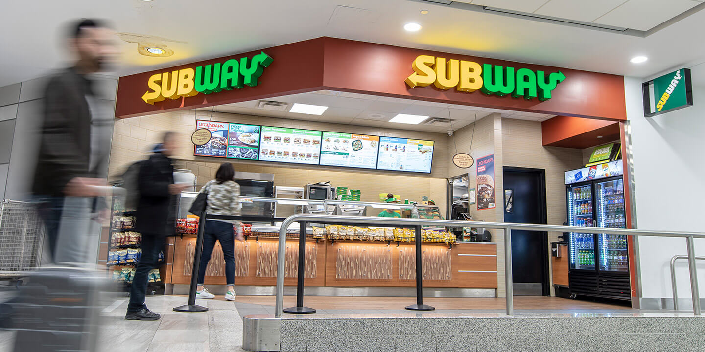 Comptoir de Subway et une petite zone pour la file avec une barrière à ceinture