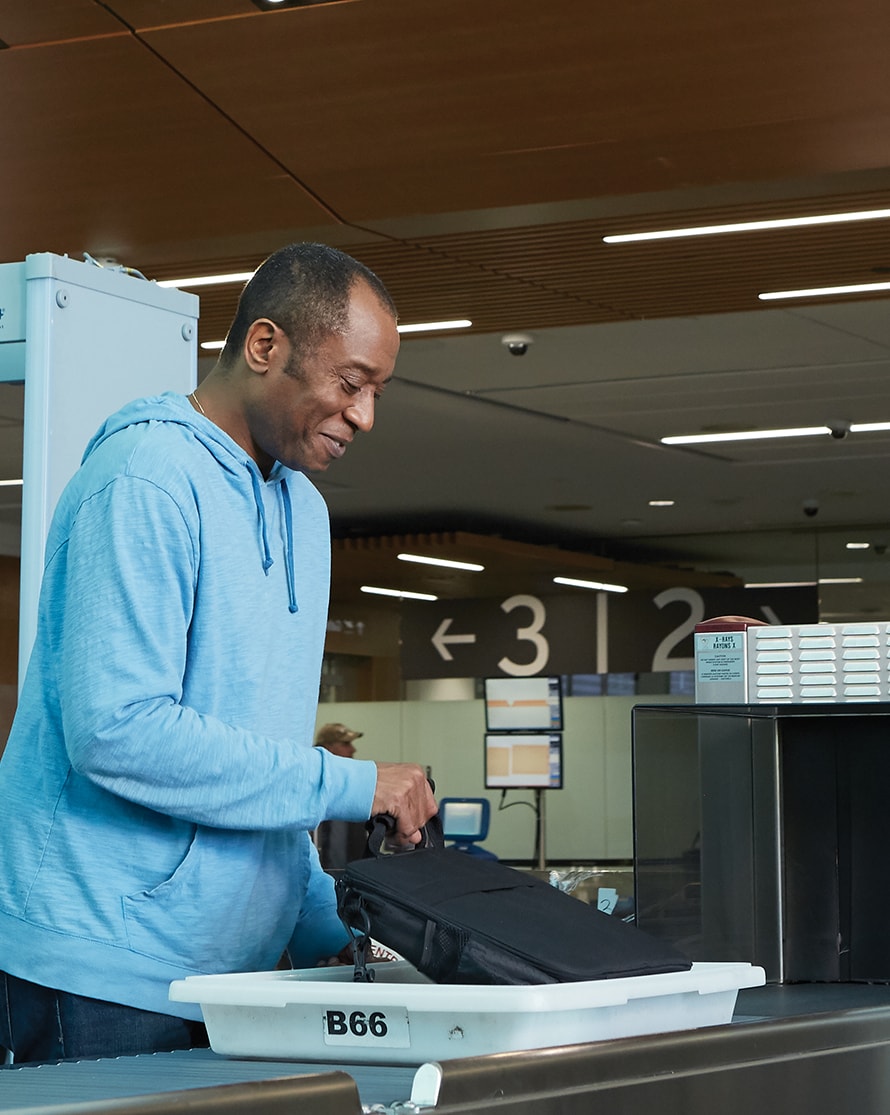 A traveller smiles while gathering his belongings in the security area