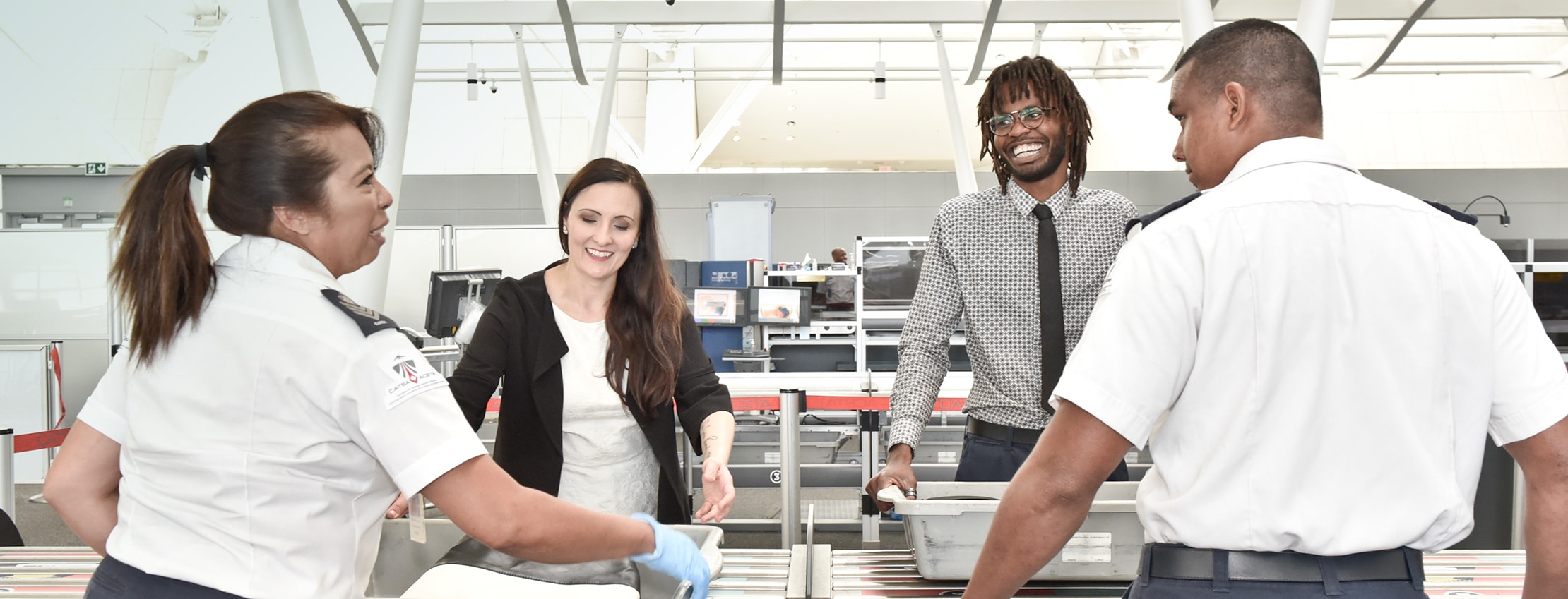 Employees and travellers smile while interacting in a Toronto Pearson security area
