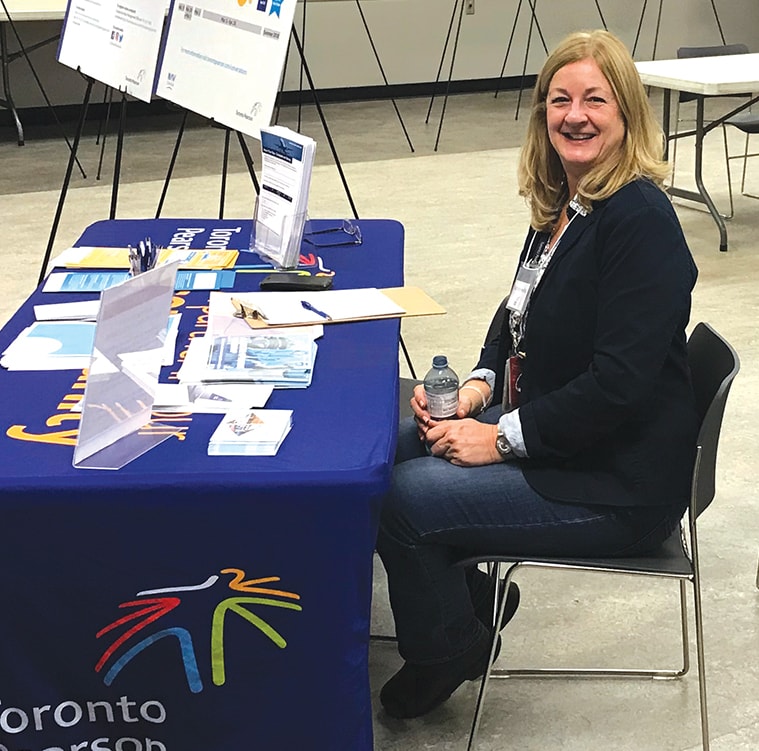 A Toronto Pearson employee works an information desk at a town hall