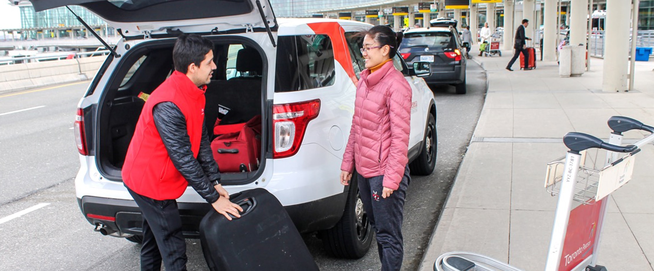Two happy travellers loading their baggage into their car at Toronto Pearson