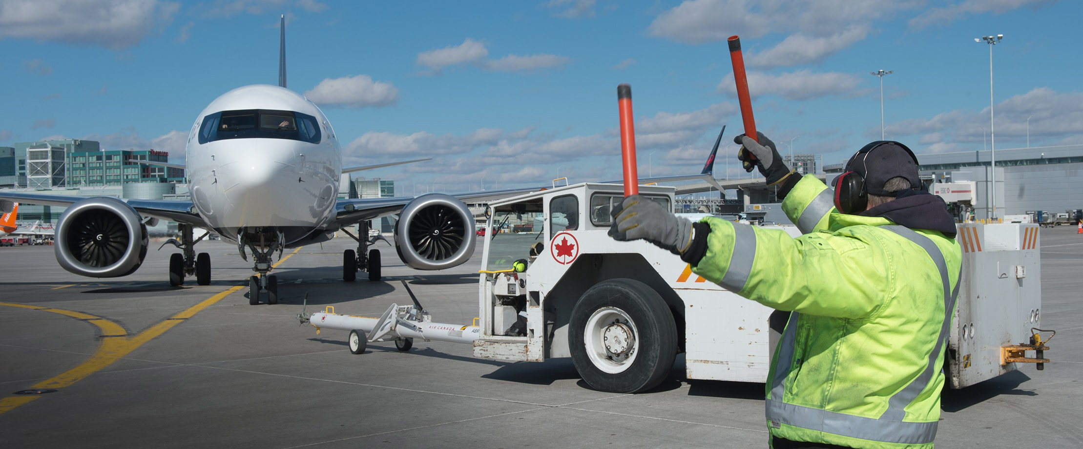 A Toronto Pearson employee directing a plane on the tarmac