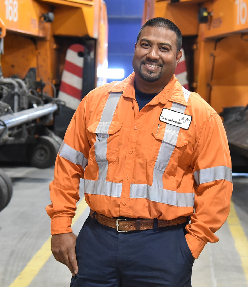 A smiling Toronto Pearson worker in a heavy-equipment area