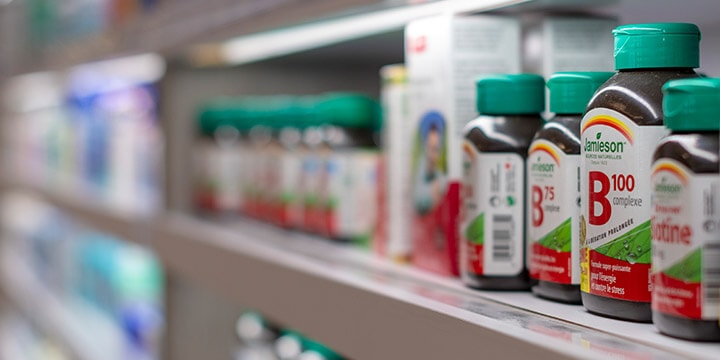 Row of vitamin bottles on pharmacy shelf. 