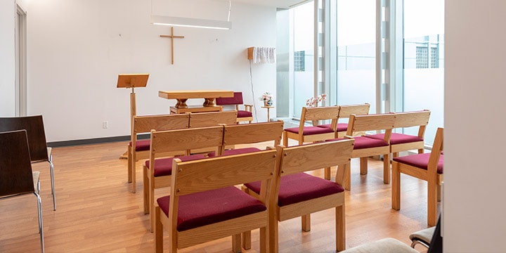 Rows of cushioned wooden benches in prayer room. 