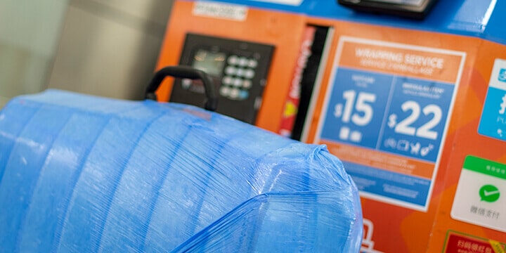 Close-up view of luggage securely wrapped in blue plastic.